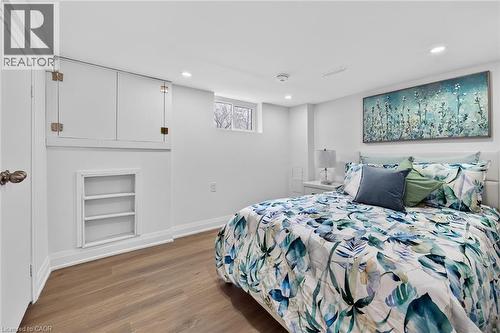 Bedroom featuring wood-finish flooring, recessed lighting, a built-in shelving niche, white baseboards, and a window - 36 Mahony Avenue, Hamilton, ON - Indoor Photo Showing Bedroom