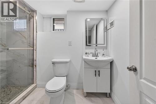 Bathroom featuring a glass-enclosed shower with marble-look wall tiling and pebble-finish flooring - 36 Mahony Avenue, Hamilton, ON - Indoor Photo Showing Bathroom