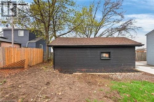 Detached garage featuring dark horizontal siding, a brown shingled roof, and a small window - 36 Mahony Avenue, Hamilton, ON - Outdoor