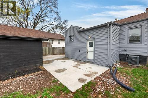 Rear exterior featuring gray horizontal siding, a white service door, and a concrete patio - 36 Mahony Avenue, Hamilton, ON - Outdoor