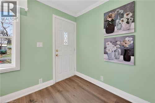 Entryway featuring a paneled door with decorative glass, wood-finish flooring, white baseboards, and crown molding - 36 Mahony Avenue, Hamilton, ON - Indoor Photo Showing Other Room