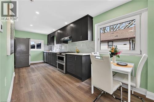 Modern kitchen featuring dark wood-finish cabinetry, stainless steel appliances including a double oven, and recessed ceiling lighting - 36 Mahony Avenue, Hamilton, ON - Indoor