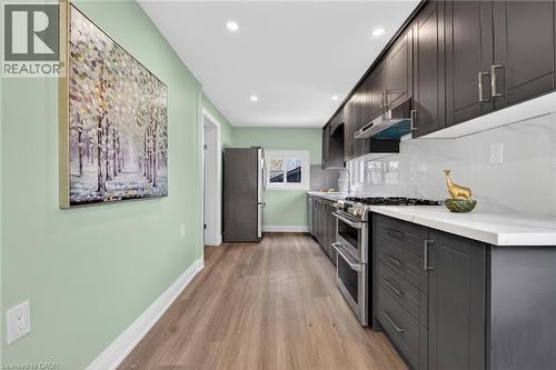 Contemporary kitchen featuring dark wood-finish cabinetry, stainless steel appliances, white countertops, and a subway tile backsplash - 36 Mahony Avenue, Hamilton, ON - Indoor Photo Showing Kitchen With Upgraded Kitchen