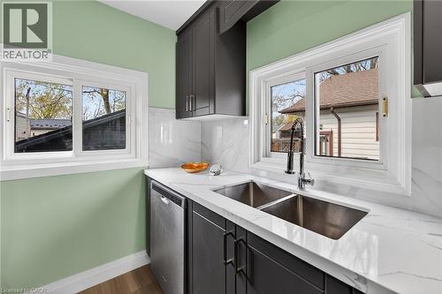 Kitchen featuring dark cabinetry, white quartz countertops, stainless steel undermount double sink with pull-down faucet, and a stainless steel dishwasher - 36 Mahony Avenue, Hamilton, ON - Indoor Photo Showing Kitchen With Double Sink