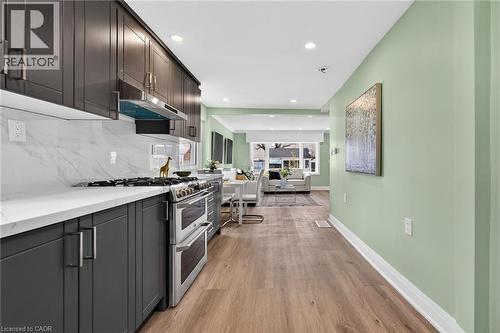 Gourmet kitchen featuring dark wood cabinetry, white countertops, and a full-height marble-patterned backsplash - 36 Mahony Avenue, Hamilton, ON - Indoor Photo Showing Kitchen With Upgraded Kitchen
