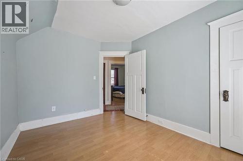 Room featuring wood-finish flooring, light blue wall paint, white baseboards, and white paneled doors with dark hardware - 115 Allen Street E, Waterloo, ON - Indoor Photo Showing Other Room