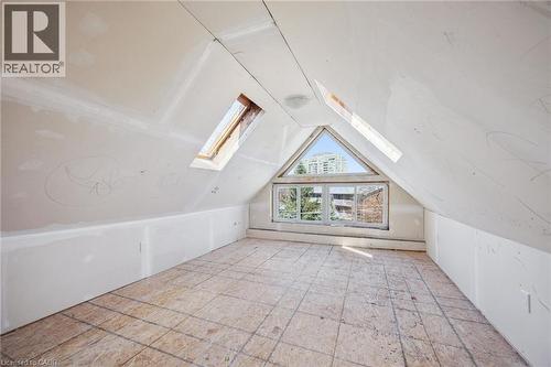 Attic space featuring sloped ceilings, two skylights, a triangular window, and plywood subflooring - 115 Allen Street E, Waterloo, ON - Indoor Photo Showing Other Room
