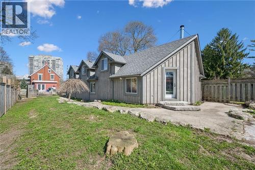 Rear exterior of the property featuring vertical wood siding, multiple dormer windows, and an asphalt shingle roof - 115 Allen Street E, Waterloo, ON - Outdoor