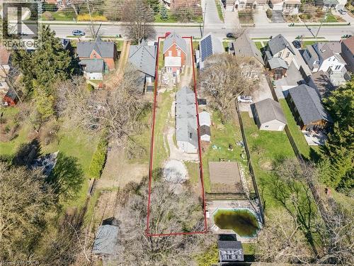 Expansive property featuring a red brick house with a gray shingled roof, a long driveway, a detached garage, and an in-ground pool - 115 Allen Street E, Waterloo, ON - Outdoor With View