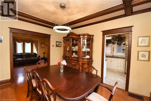 Dining area featuring a contemporary circular chandelier, rich wood-finish flooring, and exposed ceiling beams - 522 Aberdeen Avenue, Hamilton, ON - Indoor Photo Showing Dining Room