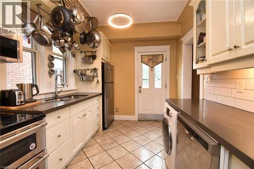Kitchen featuring white cabinetry, dark countertops, a stainless steel refrigerator, and a built-in dishwasher - 522 Aberdeen Avenue, Hamilton, ON - Indoor Photo Showing Kitchen With Double Sink