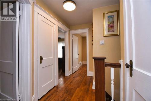 Hallway featuring wood-finish flooring, white paneled doors with bronze hardware, and a wood newel post with white balusters - 522 Aberdeen Avenue, Hamilton, ON - Indoor Photo Showing Other Room