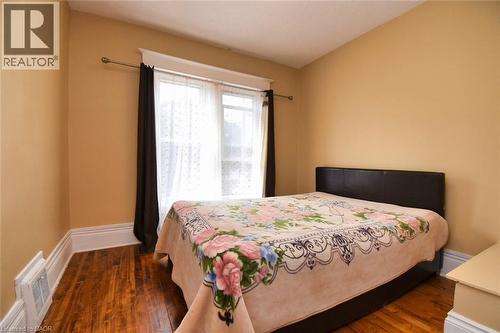 Warm-toned walls complement wood-finish flooring - 522 Aberdeen Avenue, Hamilton, ON - Indoor Photo Showing Bedroom