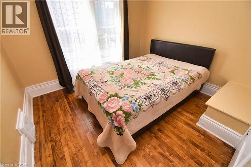 Room featuring wood-finish flooring, light-colored walls, white baseboards, and a window with dark drapes - 522 Aberdeen Avenue, Hamilton, ON - Indoor Photo Showing Bedroom