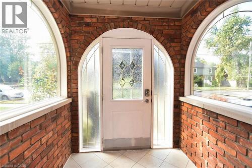 Entryway featuring an arched brick facade, a white door with decorative glass inserts, and complementary arched sidelight windows - 522 Aberdeen Avenue, Hamilton, ON - Indoor Photo Showing Other Room