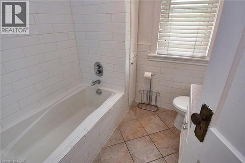 White subway tile surrounding a built-in bathtub with chrome fixtures, complemented by earth-toned square floor tiles - 522 Aberdeen Avenue, Hamilton, ON - Indoor Photo Showing Bathroom