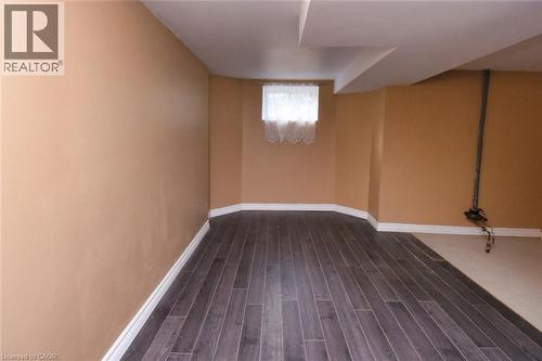 Interior space featuring wood-finish flooring, light tan wall paint, white baseboards, and a window with white curtains - 522 Aberdeen Avenue, Hamilton, ON - Indoor Photo Showing Other Room