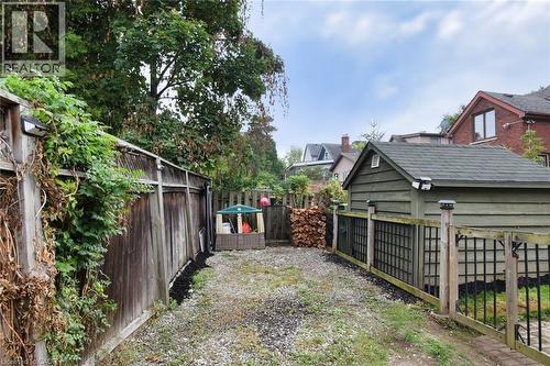 Spacious rear yard area featuring a detached shed with a shingled roof, a full wooden fence, and a gate with decorative lattice panels - 522 Aberdeen Avenue, Hamilton, ON - Outdoor