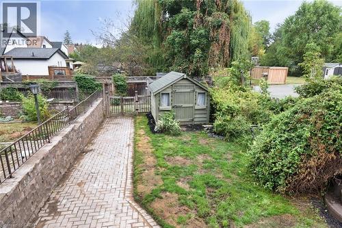 Backyard featuring a paved pathway, a built-in wooden shed, and mature perimeter trees - 522 Aberdeen Avenue, Hamilton, ON - Outdoor