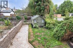 Backyard featuring a paved pathway, a built-in wooden shed, and mature perimeter trees - 