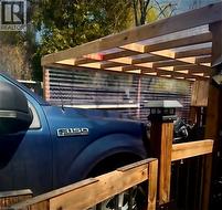 Wood-framed carport with a clear corrugated panel roof and side panels, featuring a wooden railing and a post-mounted light fixture - 