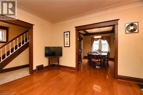 Spacious interior featuring warm wood-finish flooring, substantial dark wood trim, a wide doorway opening, a staircase with white balusters, and a visible dining area with a tray ceiling - 522 Aberdeen Avenue, Hamilton, ON - Indoor Photo Showing Other Room
