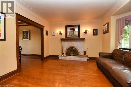Living area featuring wood-finish flooring and a fireplace with a stone surround and a decorative metal screen - 522 Aberdeen Avenue, Hamilton, ON - Indoor Photo Showing Living Room With Fireplace