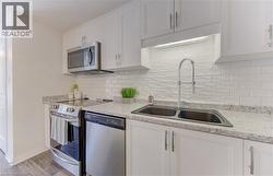 Bright kitchen featuring white cabinetry and granite-look countertops - 