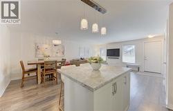 Kitchen island with light-toned countertop, pendant lighting, wood-finish flooring, and white cabinetry - 