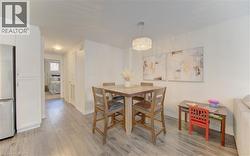 Open-concept dining area featuring wood-finish flooring, a contemporary drum pendant light fixture, and white painted walls - 