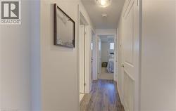 Hallway featuring wood-finish flooring, light-colored walls, white trim, and recessed lighting - 