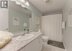 Bathroom featuring a white vanity with a light-toned countertop, an oval undermount sink, and a chrome faucet - 