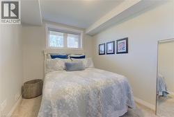 Carpeted bedroom featuring a white window frame, white baseboards, and neutral wall paint - 