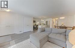 Open-concept living space featuring wood-finish flooring, white paneled doors, recessed lighting, and a modern kitchen with stainless steel appliances - 