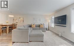 Open-concept living area featuring wood-finish flooring, recessed lighting, and multiple windows - 