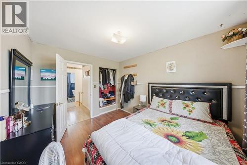 Bedroom featuring wood-finish flooring, two-tone painted walls, a built-in open closet with shelving, and a flush-mount ceiling light fixture - 116 Gainsborough Road, Hamilton, ON - Indoor Photo Showing Bedroom