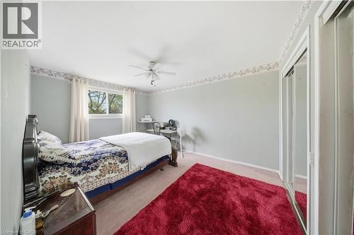 Light-colored walls featuring a decorative border, ceiling fan, carpet flooring, a window with curtains, and mirrored sliding closet doors - 116 Gainsborough Road, Hamilton, ON - Indoor Photo Showing Bedroom