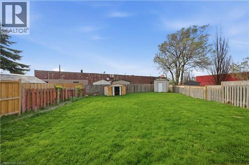 Expansive fenced yard featuring a large grass area, mature trees, and two storage sheds - 116 Gainsborough Road, Hamilton, ON - Outdoor With Backyard