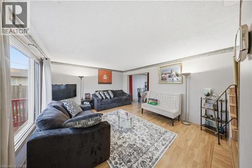 Living area featuring light wood-finish flooring, white walls with decorative border, and a large window providing natural light - 116 Gainsborough Road, Hamilton, ON - Indoor Photo Showing Living Room