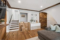 Living area featuring wood-finish flooring, a white shiplap ceiling with recessed lighting, and dark wood beams - 