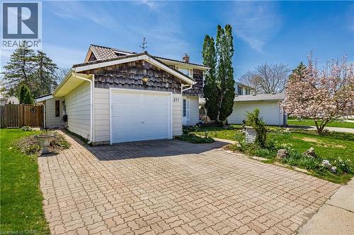 Exterior featuring a detached garage with a white overhead door, natural wood shake siding accents, and a complementary light-toned siding - 277 Blackacres Boulevard, London, ON - Outdoor