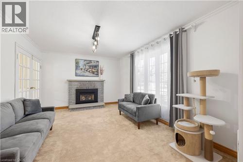 Spacious room featuring a stone fireplace with a black insert, light-toned carpet, and crown molding - 277 Blackacres Boulevard, London, ON - Indoor Photo Showing Living Room With Fireplace