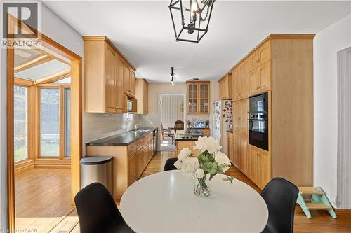 Kitchen featuring light wood cabinetry, built-in double ovens, dark countertops, white subway tile backsplash, and wood-finish flooring - 277 Blackacres Boulevard, London, ON - Indoor