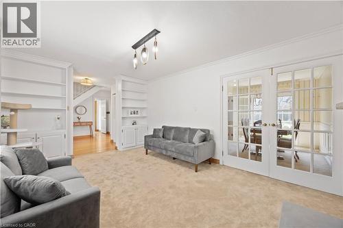 Carpeted living area featuring white built-in shelving, crown molding, and a contemporary ceiling fixture - 277 Blackacres Boulevard, London, ON - Indoor Photo Showing Living Room
