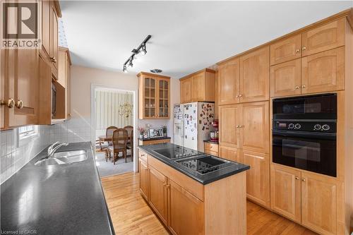 Kitchen featuring wood-finish cabinetry, black countertops, and hardwood flooring - 277 Blackacres Boulevard, London, ON - Indoor Photo Showing Kitchen With Double Sink