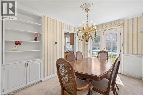 Dining space featuring French doors, a brass chandelier, built-in shelving with lower cabinetry, and wainscoting - 277 Blackacres Boulevard, London, ON - Indoor Photo Showing Dining Room