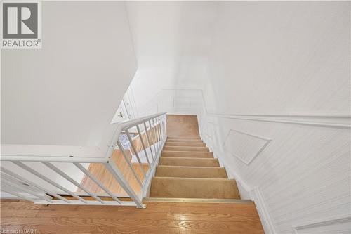 Staircase featuring carpeted treads, wood-finish flooring at the landing, a white metal balustrade, and textured wall finishes with chair rail detailing - 277 Blackacres Boulevard, London, ON - Indoor Photo Showing Other Room