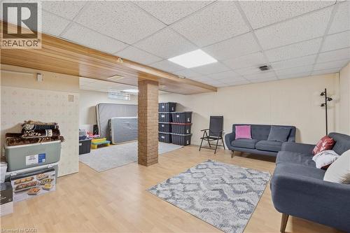 Spacious room featuring wood-finish flooring, a drop-tile ceiling with integrated lighting, and a brick-clad support column - 277 Blackacres Boulevard, London, ON - Indoor