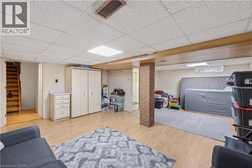 Finished basement featuring wood-finish flooring, drop ceiling with recessed lighting, and a brick-clad support column - 277 Blackacres Boulevard, London, ON - Indoor Photo Showing Basement