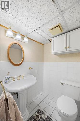 Pedestal sink with brass-finish faucet, white subway tile wainscoting, and white floor tiles - 277 Blackacres Boulevard, London, ON - Indoor Photo Showing Bathroom